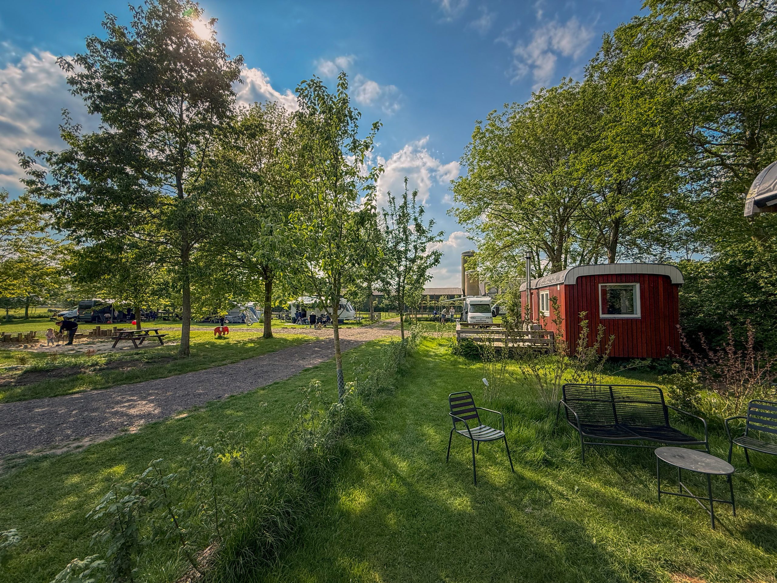 Pipowagen Janne aan de rand van het kampeerveld op Boerderij de IJsselhoeve in vol seizoen